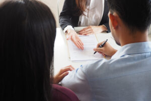 New couple signing contract buying a new property after marriage for living together at a real estate company.